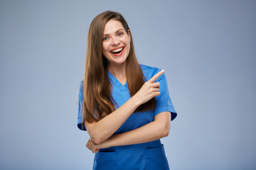 Smiling nurse woman pointing finger at side. Isolated female portrait.