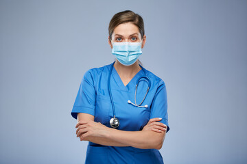 Serious nurse woman or doctor in blue medical mask and suit. Isolated female portrait.
