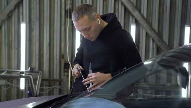 Master Blows Dust From Car Glass. Scola Repair