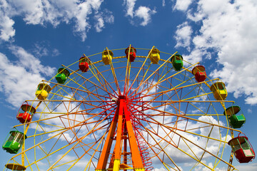 Attraction (carousel) ferris wheel on the background of the cloudy sky