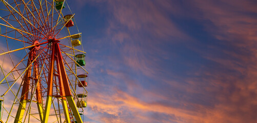 Attraction (carousel) ferris wheel against the background of a romantic evening sky