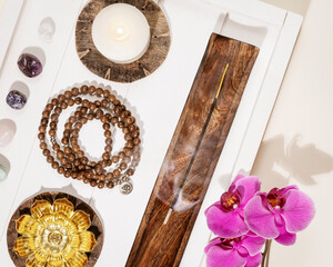 Self-care, healing flat lay with rosary beads, candles, aroma sticks, chakra stones and orchid...