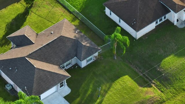 Aerial view of typical contemporary american private house with roof top covered with asphalt shingles and green lawn on yard