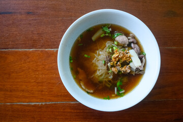 Asian delicatessen, beef noodles with soup on wood table.