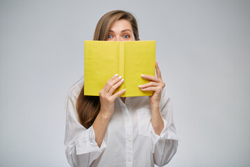 Fototapeta premium Woman covering her face with yellow book, isolated female portrait.
