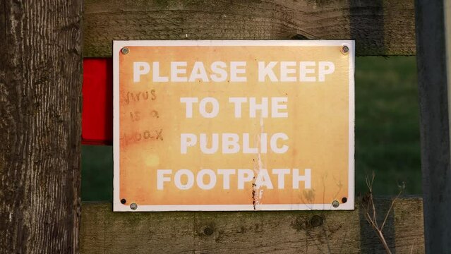 Sign saying please keep to the public footpath and virus is a hoax