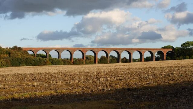 Timelapse of a red brick viaduct in a field against a cloudy sky