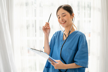 Professional Woman working in a hospital holding a folder and smiling, Medical concept of Asian confident female doctor in blue medical uniform with stethoscope
