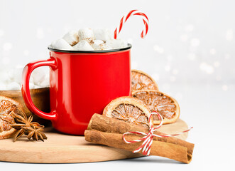 warming Christmas drink in a mug with marshmallows, sweets and spices on a light background