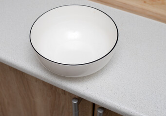 Round deep plate on the edge of the table.