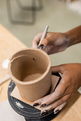 Fototapeta na wymiar Cropped view of african american craftswoman cutting clay in pottery workshop.