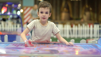 Boy trying to win in the game of air hockey on the playground - 537849649