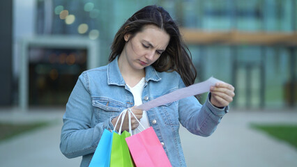 A girl with a cash receipt in her hands on the background of a shopping center after shopping - 537849841