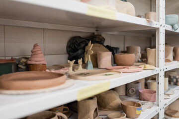 different clay sculptures on shelves of pottery shop.