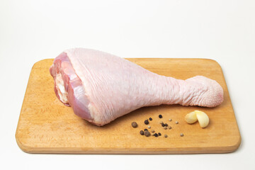 Raw turkey leg on a wooden board on a white background. Fresh turkey meat