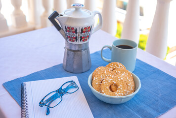 Breakfast or break outdoor on a white table with coffe cup and whole grain biscuits. Vintage ceramic coffee maker.