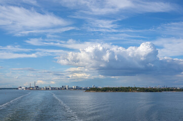 View from the sea to Helsinki skyline on summer evening. Water trail behind ferry in the Baltic sea in the foreground