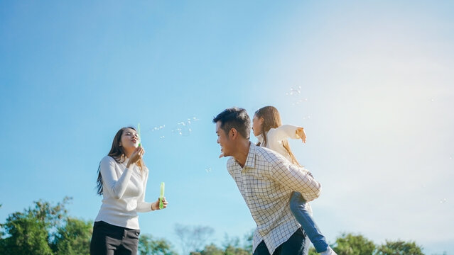 Happy asian family in the garden They are having fun playing and blowing bubbles. and enjoyed ourselves together in the green garden. Family enjoying sunny fall day in nature.