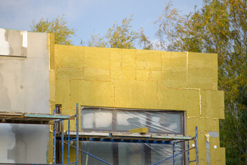 External wall insulation. Energy efficiency house wall renovation for energy saving. Exterior house wall heat insulation with mineral wool, building under construction.