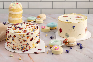 table of sweet products of fine pastry with macarons alfajores chocolate dipped cookies muffins donuts and cakes decorated with natural dry edible flowers