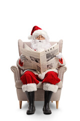 Santa claus sitting in armchair and reading newspaper