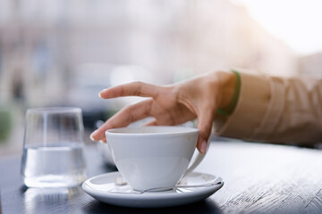 A hand reaches for vending coffee cup on table at street cafe        