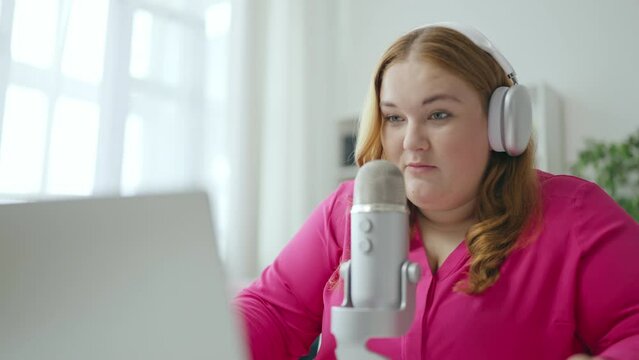 Female radio anchor in headphones speaking in microphone, entertainment show