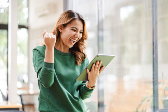 Asian girls are excited about victory. hand holding a digital tablet at her office