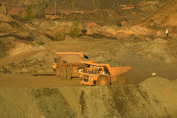 A large open-pit dump truck carries iron ore from the quarry to the surface of the earth. Open pit mining technologies. View of the upper horizons of the quarry. Technique for mining. © MaksimM