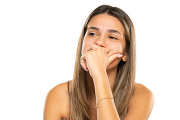 Boring young woman with long hair looking to side and thinking on a white studio background