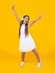 Fototapeta na wymiar singing teen girl listen music in headphones and dancing on yellow background