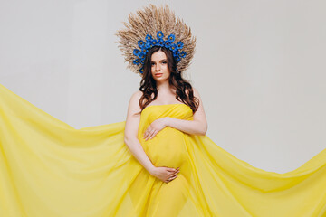 Cute pregnant woman wrapped in a yellow cloth and with a wreath on her head.The concept of love for...