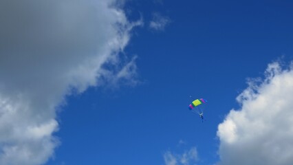 Adrenaline addiction of a person from extreme sports, parachutist flying in the blue sky with a...