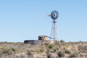 Windmill with a watertank inside an old corrugated iron dam