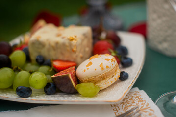 White plate on a green table with delicious food and wine outdoors on summer day. Romantic date.
