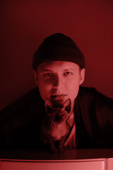 Young handsome guy with sphinx on red background.