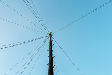 Fototapeta premium Abstract view of telephone wires connecting to a single wooden telegraph pole with a large bird sitting on the top in early sunset.