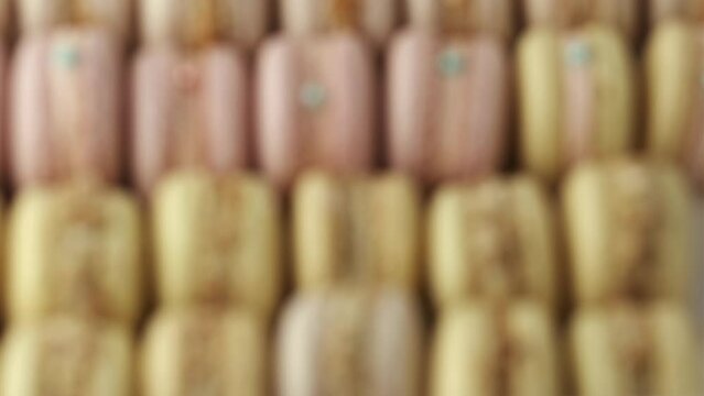 Gift box full of fresh yellow and pink macaroons cookies. French traditional dessert. Delivery of confectionery. A lot of macaroons go into a blurred background. 