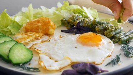 Cinematic footage of a breakfast of fried eggs and fried vegetables and greens. Squeeze a lime wedge over the fried beans. Healthy and hearty breakfast at home or in a restaurant. Proper nutrition.