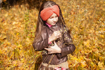 a seven-year-old girl in a leather jacket against the background of yellow leaves in autumn