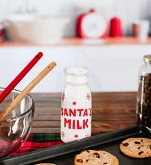 Fotobehang Closeup of a Santa's milk bottle with cookies on a wooden table © Tamara Sales/Wirestock Creators