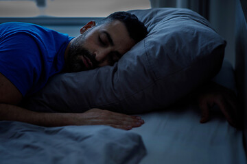 Sleeping young arab sleeping night, resting peacefully in a comfortable bed with gray linens with closed eyes, free space.