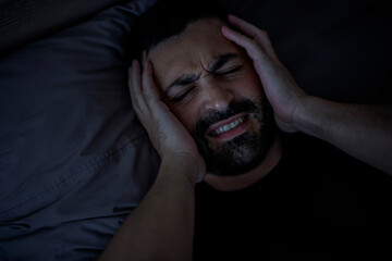 A sad millennial Arab man is worried, suffers from insomnia and headache.