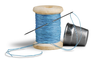 Spool with needle and thimble isolated on white