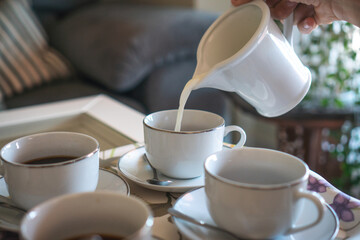 close-up of pitcher pouring milk into coffees