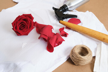 kit for dyeing a t-shirt with a rose flower press, a spray with a fixative, water and a rolling...