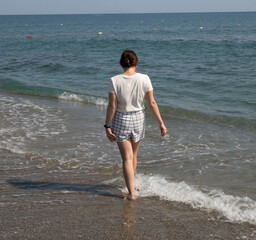 Fototapeta na wymiar A girl walking along the beach