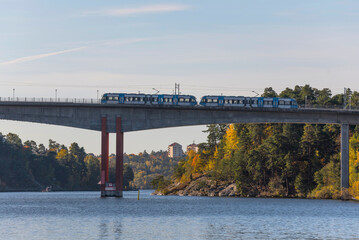 Tram passing on a bridge at the district Alviks Strand a sunny a color full autumn day in Stockholm