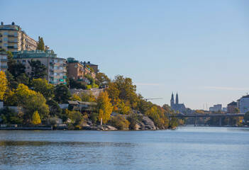 Fototapeta premium Apartment houses on a cliff in the district Kungsholmen, skyline with church towers a sunny a color full autumn day in Stockholm