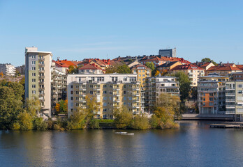 Waterfront apartment houses and canoers passing the island Lilla Essingen a sunny a color full autumn day in Stockholm
